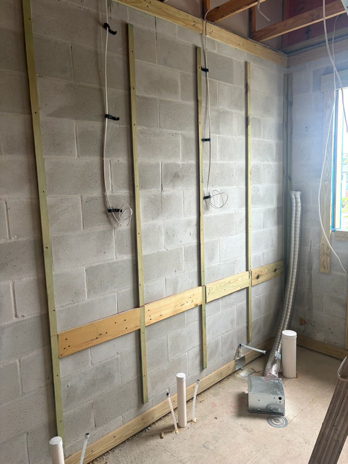 Construction progress: Plumbing and electrical rough-in along a block wall